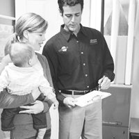 American Standard Contractor showing paperwork to woman holding child